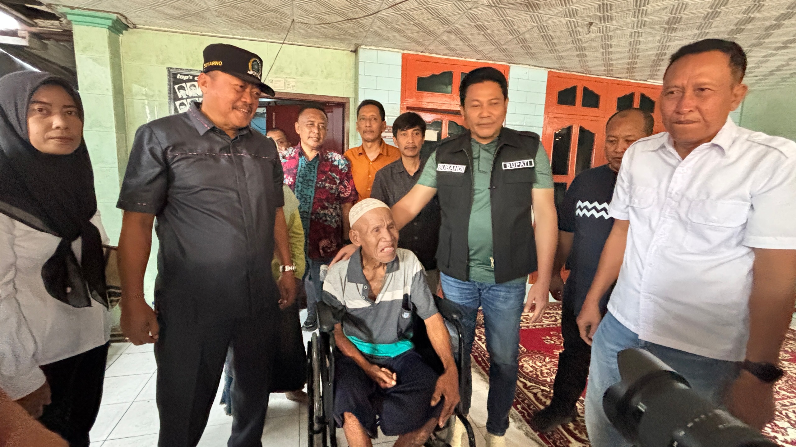 Bupati Sidoarjo H. Subandi didampingi Kadinsos dan anggota DPRD Sidoarjo menyalurkan bantuan kursi roda serta meninjau RTLH di Kecamatan Prambon, Sabtu (1/8/2026). (FT/Wawan)