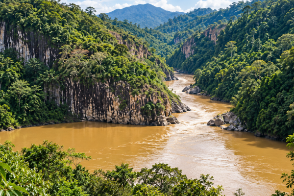 Panorama tebing batu menjulang yang dikelilingi hutan hijau dan aliran sungai di kawasan wisata Batu Dinding, Desa Marah Haloq, Kecamatan Telen, Kabupaten Kutai Timur. (dok.Kecamatan Telen)
